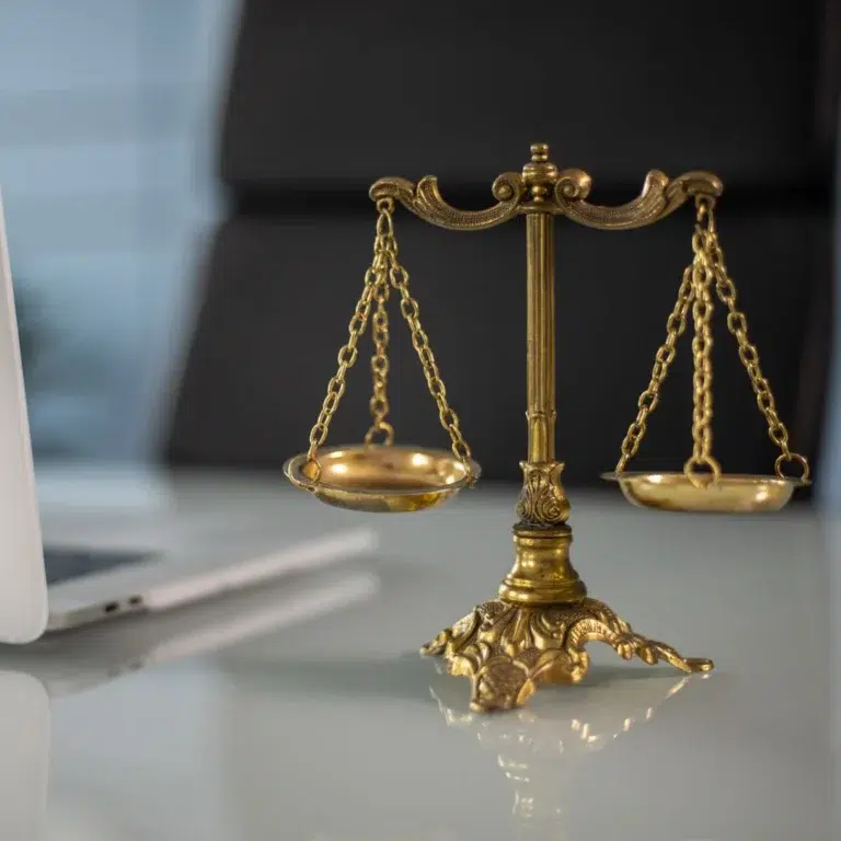 Balanza de la justicia junto a un computador portátil, símbolo del uso de la inteligencia artificial en la litigación