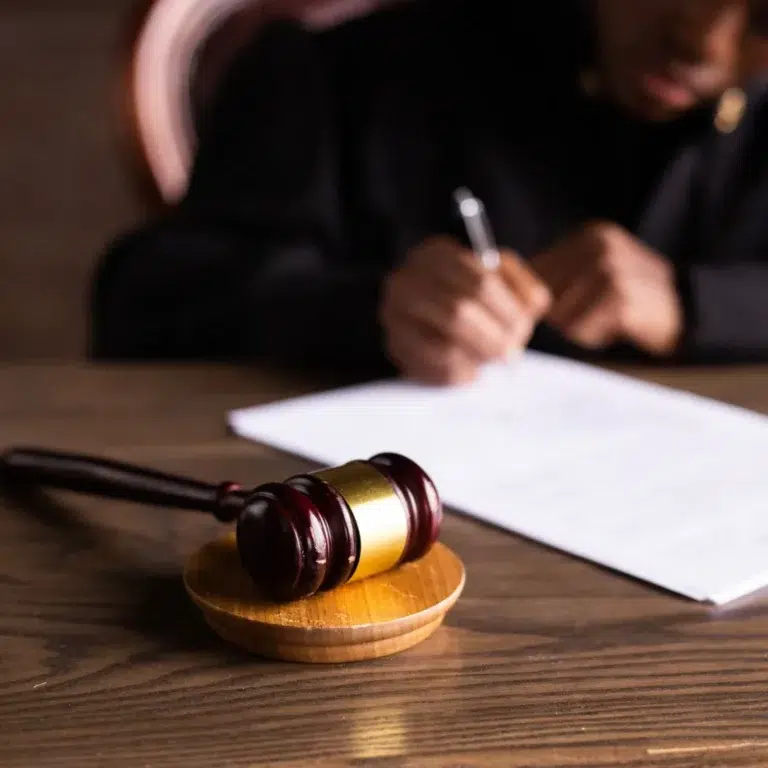 Juez firmando una sentencia junto a un mazo de madera, que representa la exigencia de los tribunales en la tutela laboral